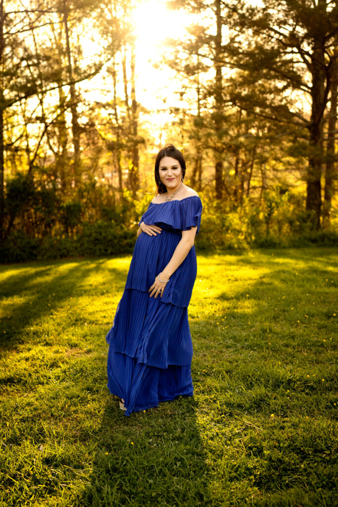 Full length picture of pregnant woman in blue dress during sunset