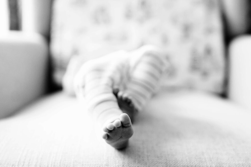 black and white image of newborn baby feet while baby is laying on chair