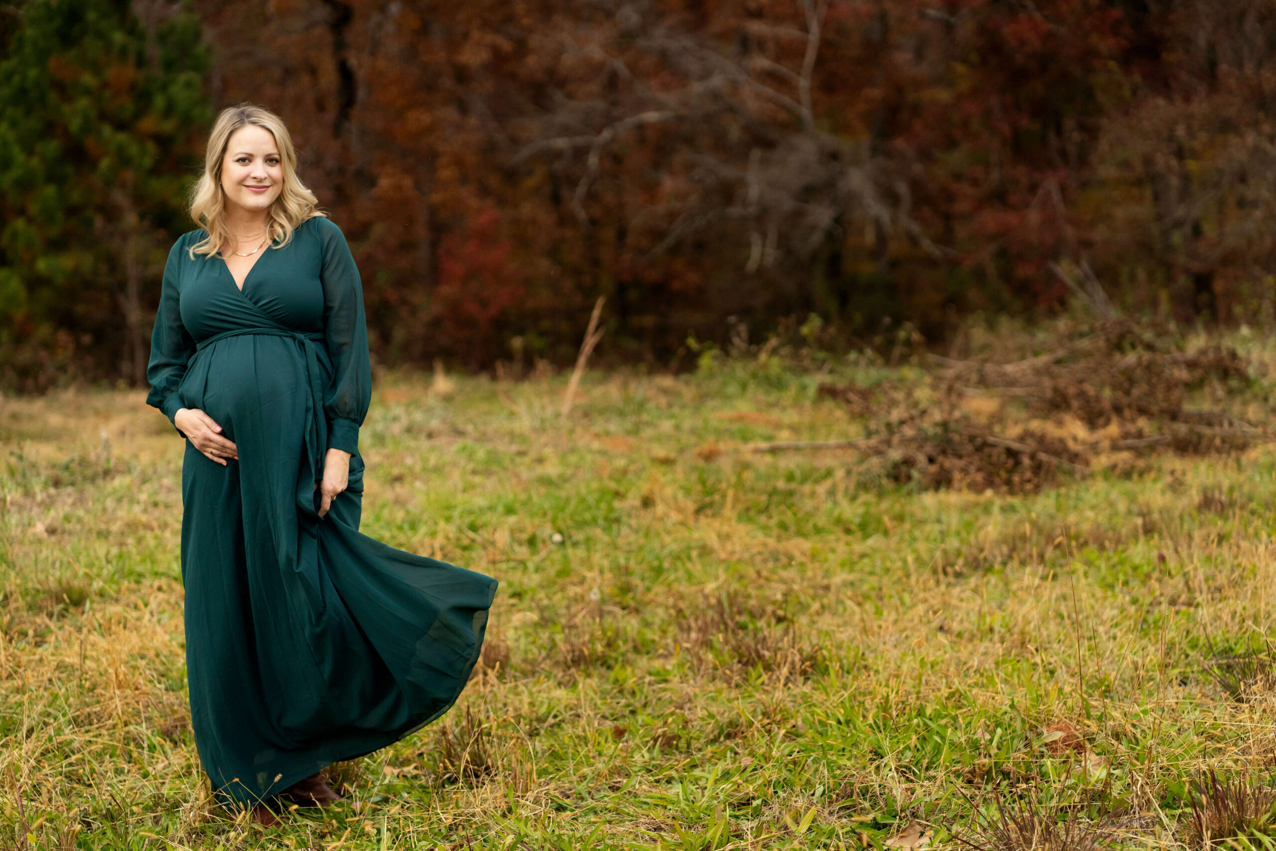 Pregnant woman in long green dress in field.