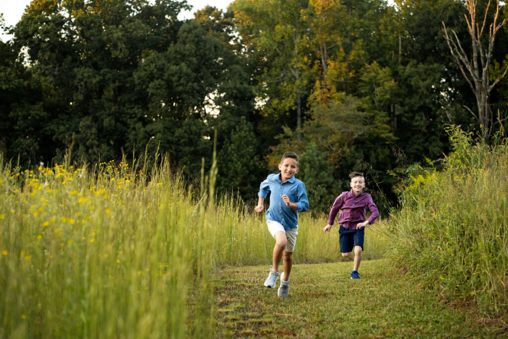 Two young brothers running in field of tall grass. 