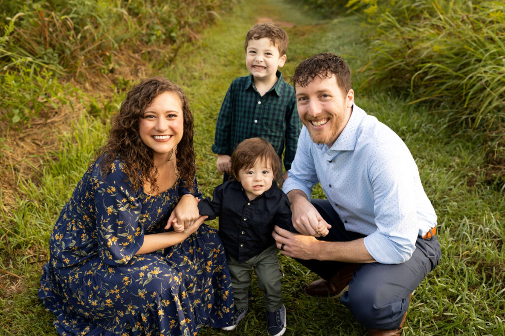 family of four smiling at camera in field looking up